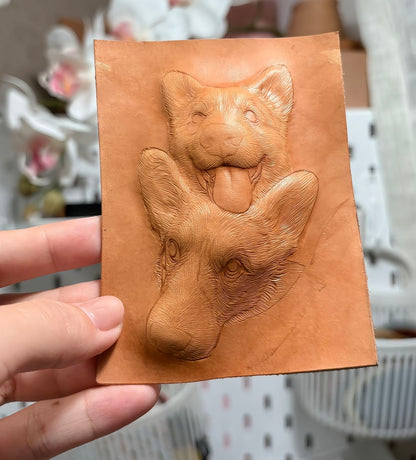 Two corgi portraits hand-carved in uncolored leather before the coloring stage