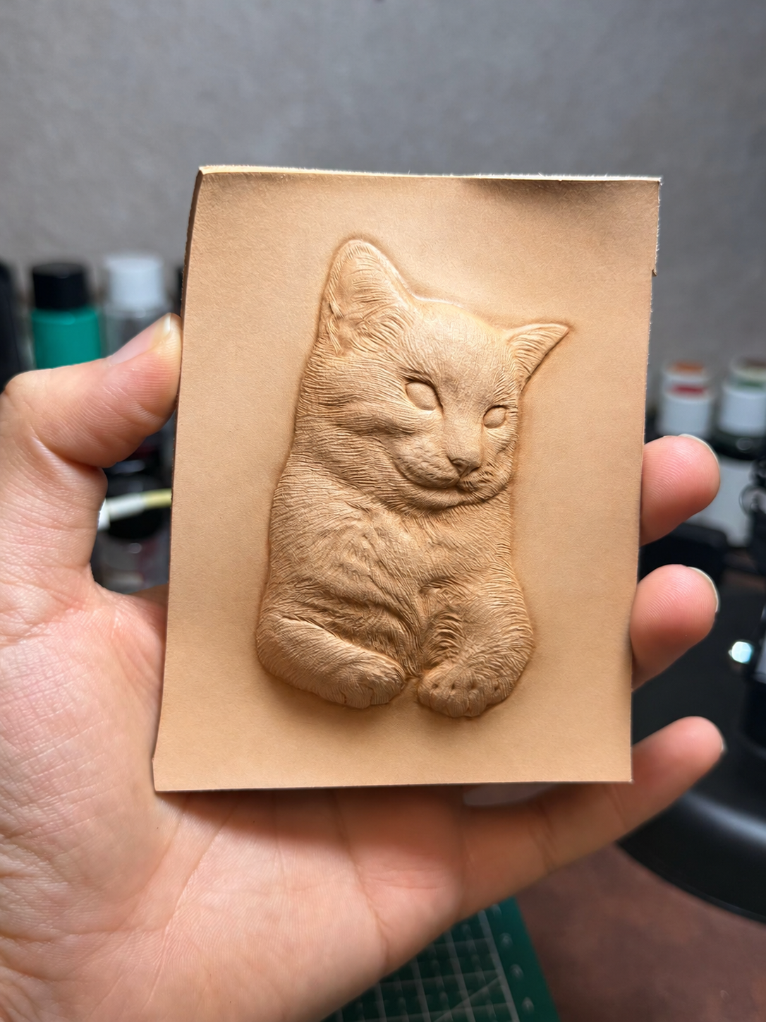 Raised cat portrait and fur details hand-carved into uncolored leather